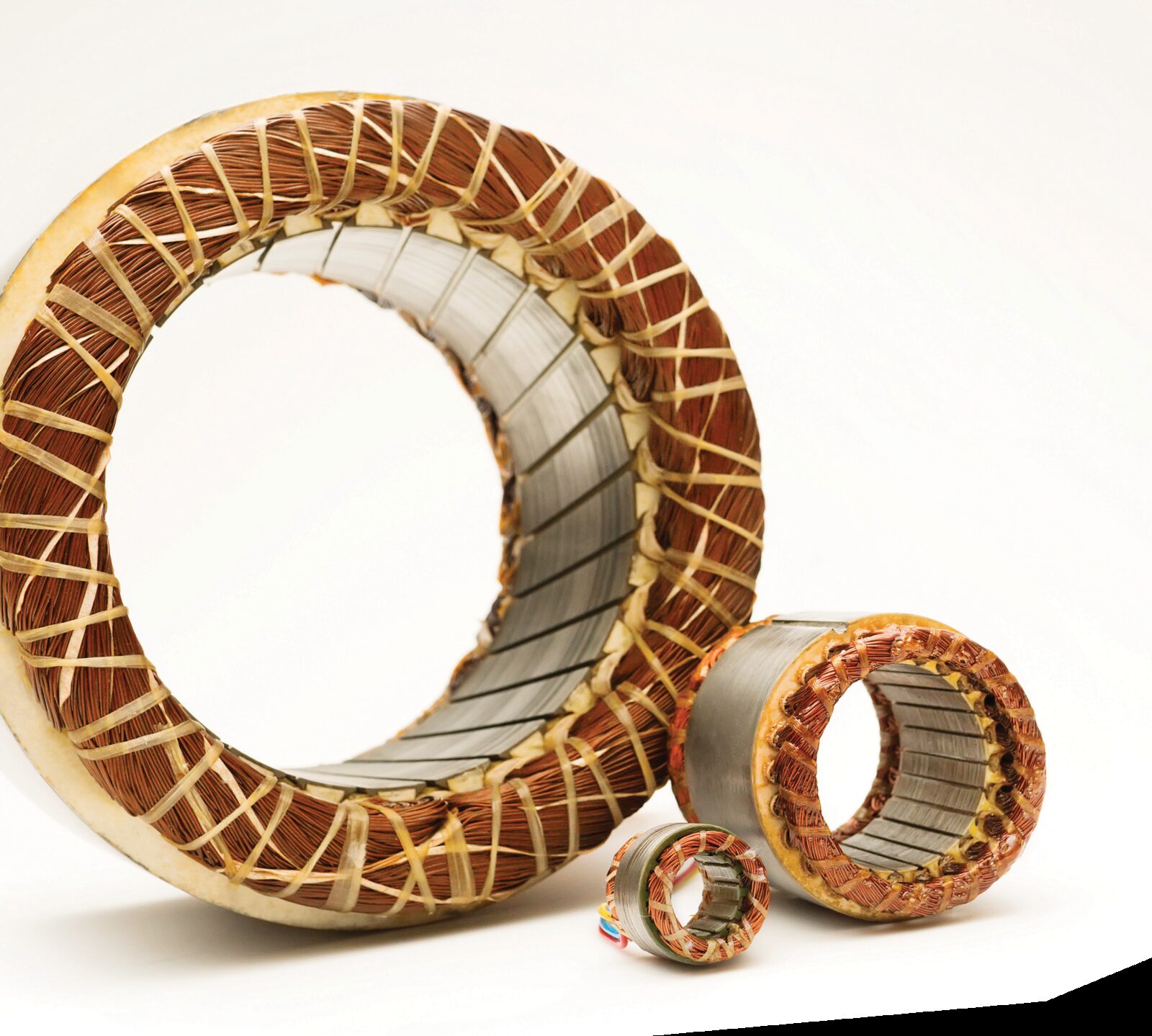 Three wound stator assemblies of different diameters, showing copper windings and laminated cores.